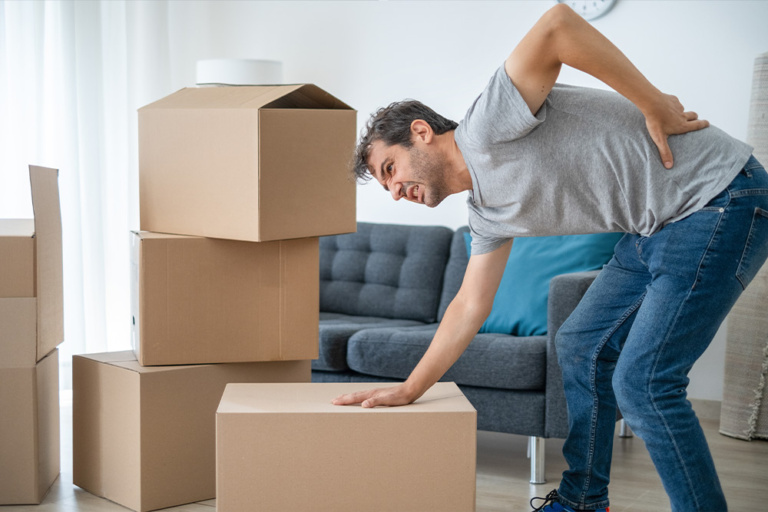 A man is having backache while lifting moving boxes